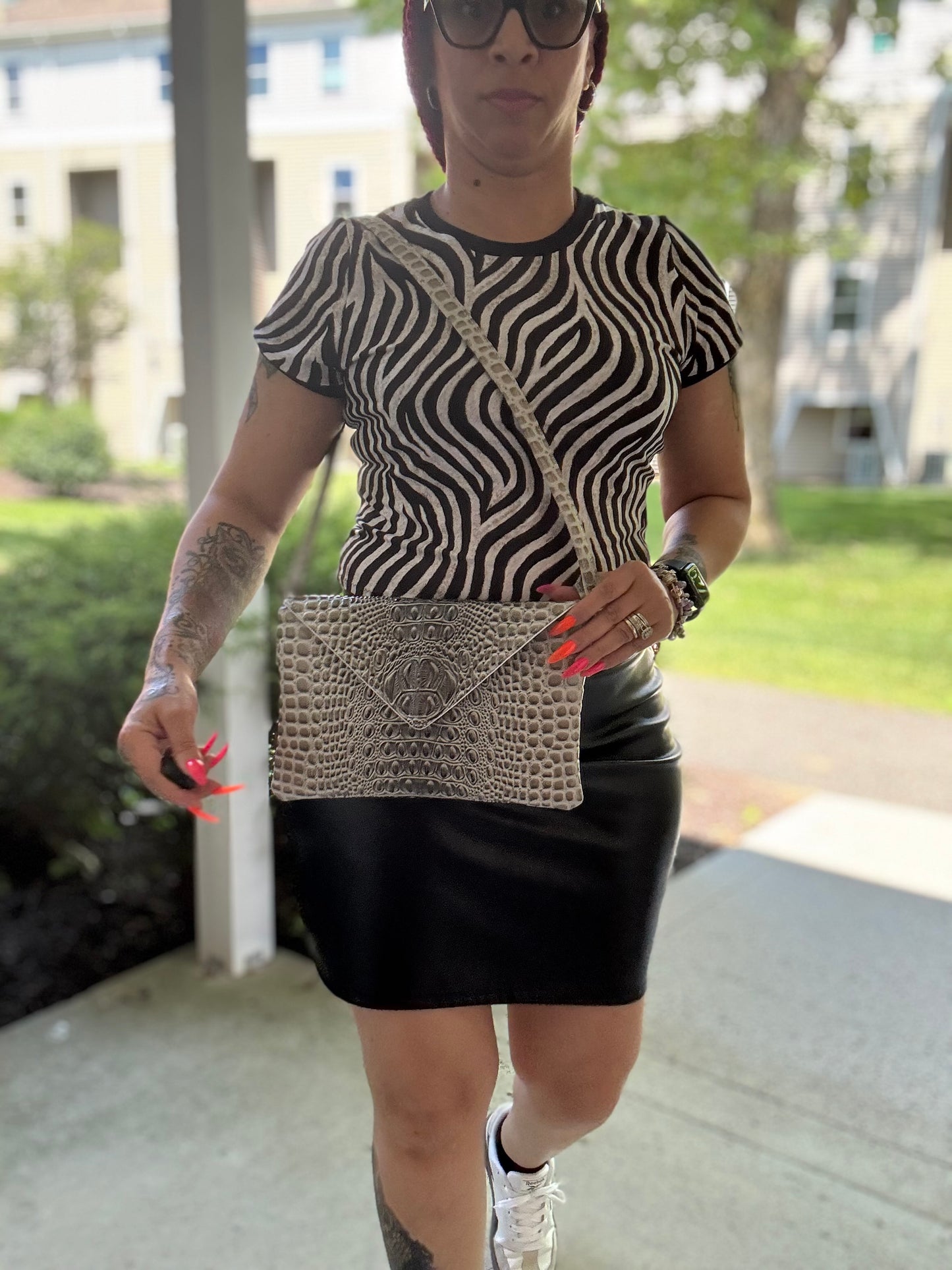 Gray croc vinyl envelope crossbody bag worn with zebra print top and black skirt